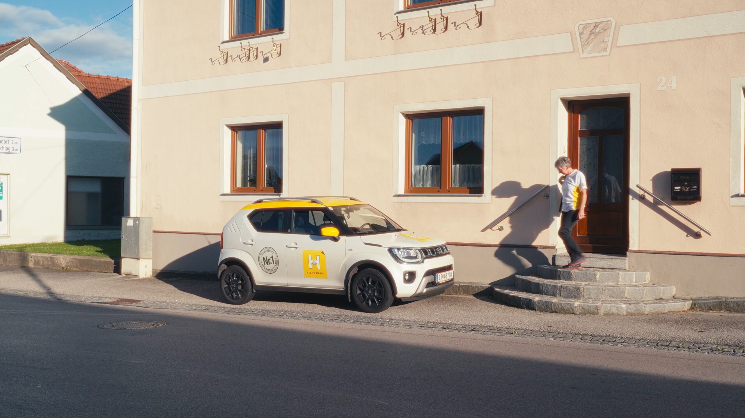 Eine mobile Pflegerin vom Hilfswerk neben ihrem Auto